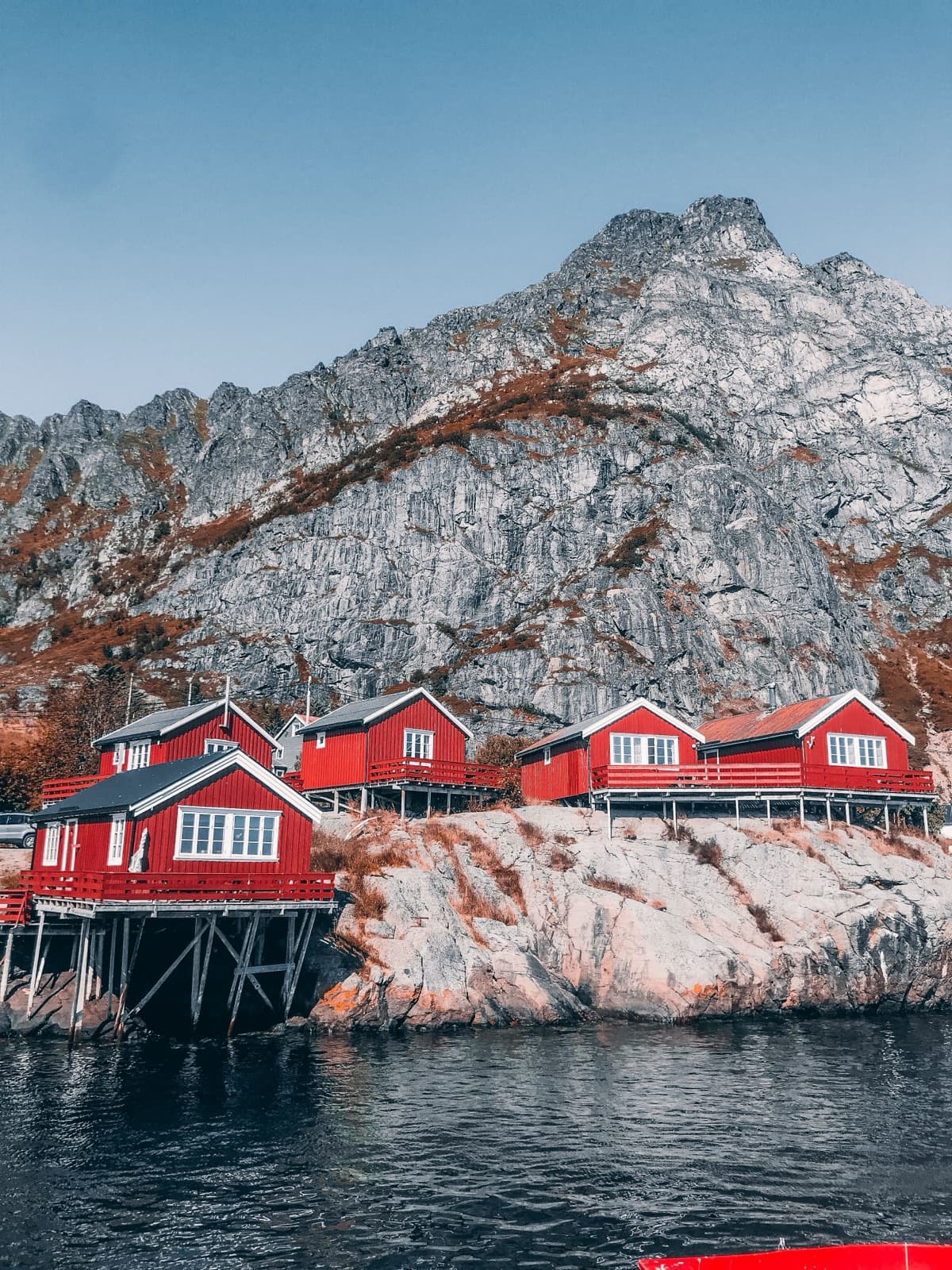 Fiskerhuset: røde rorbuer i to etasjer under fjellet.